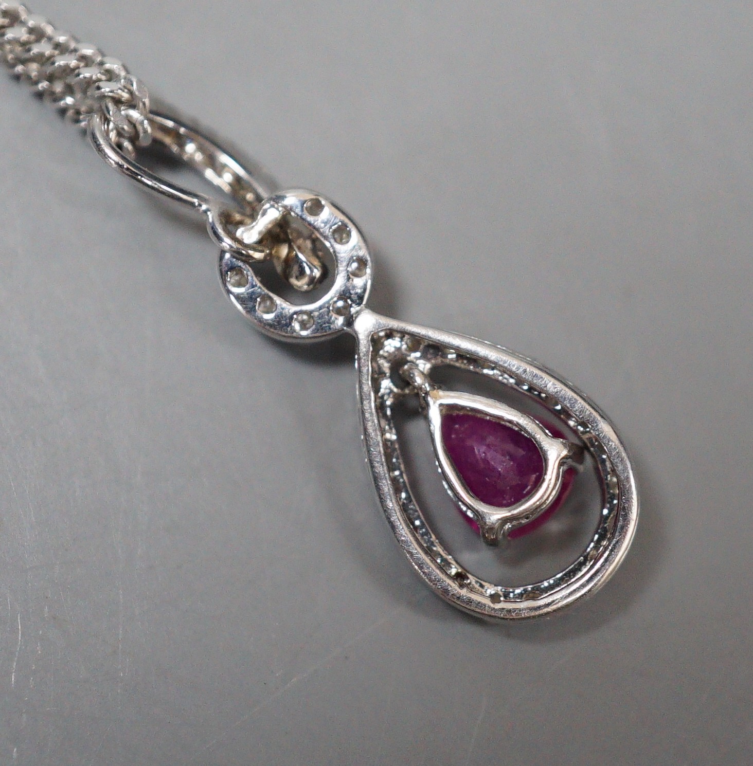 A modern white metal, ruby and diamond chip set pear shaped drop pendant, 20mm, on a 9ct white gold chain, 44cm, gross weight 5.3 grams.
